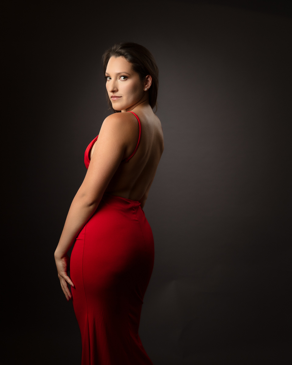Woman wearing red dress against dark background, profile pose