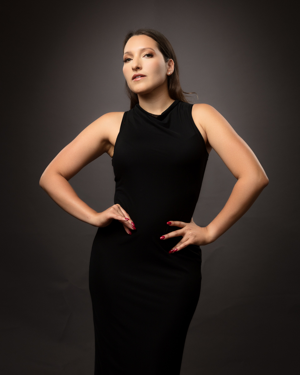 Woman in black sleeveless dress against grey background