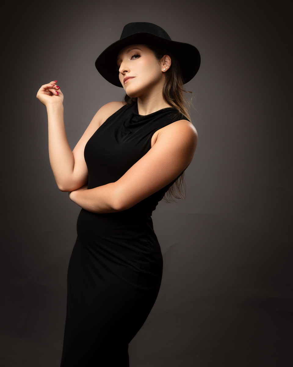 Woman in black halter dress wearing wide-brimmed black hat