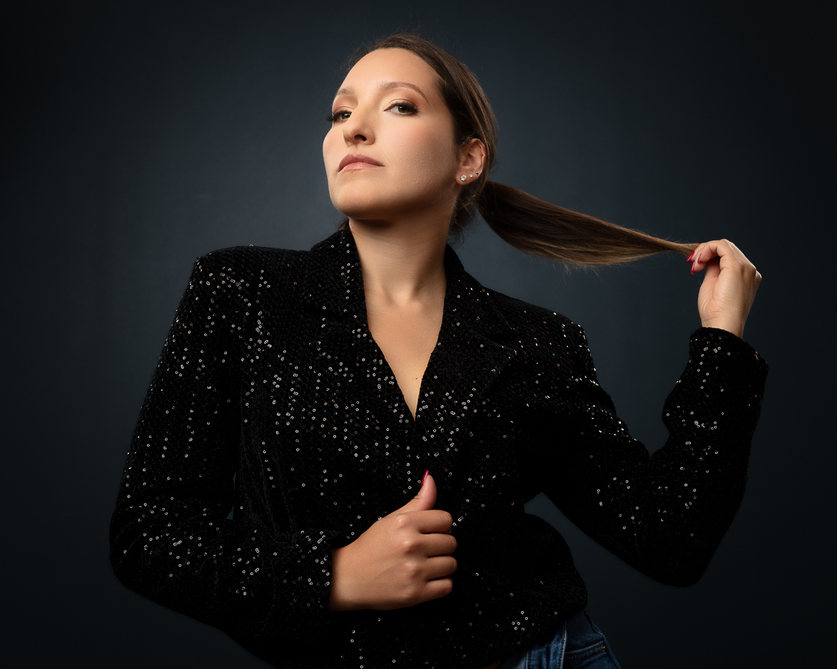 Woman in black sequined blazer against dark background