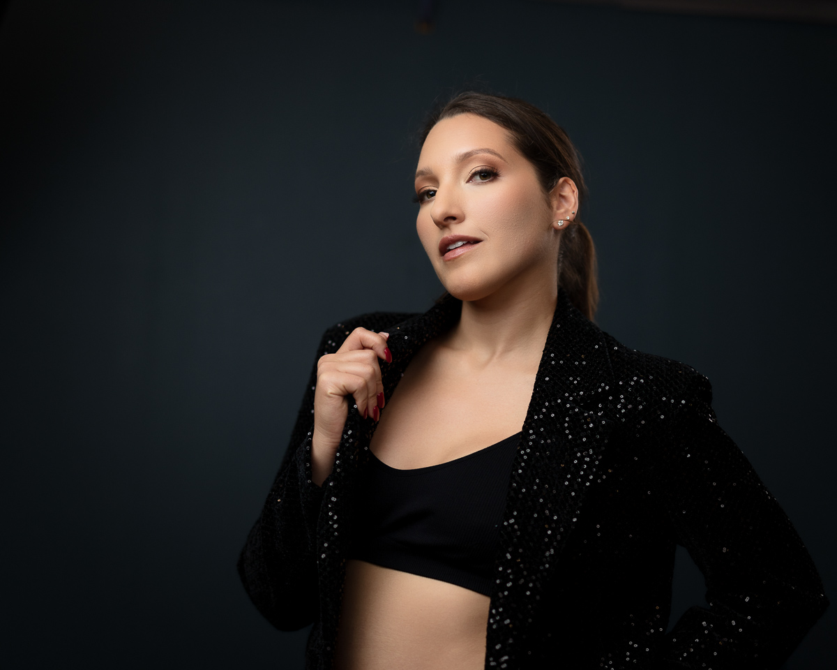Woman in black sequinned blazer against dark background