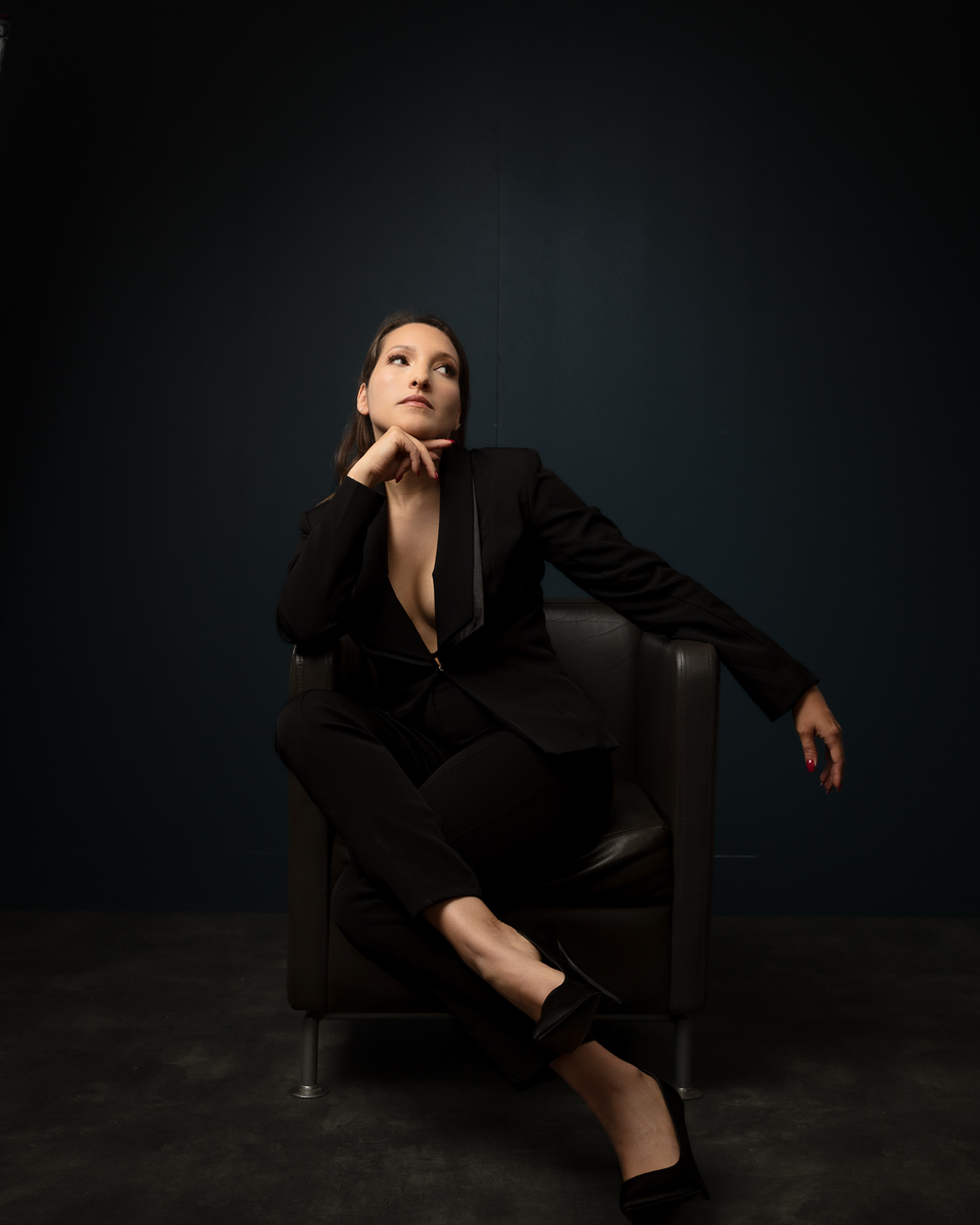 Professional woman in black suit sitting thoughtfully on chair