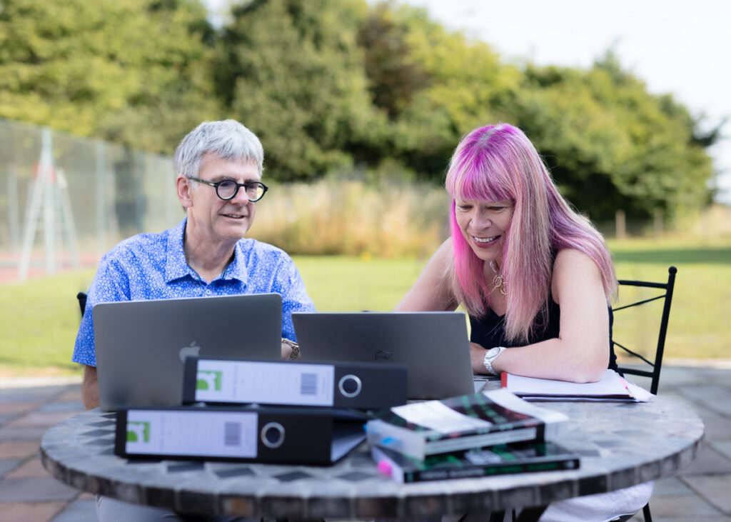 Two people working on laptops outdoors.
