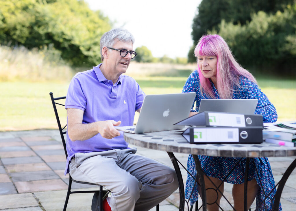 Two people working on laptops outdoors.