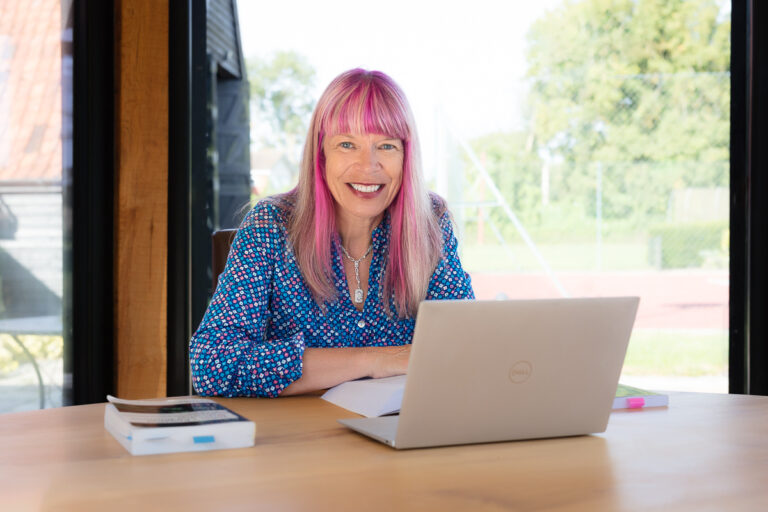 Woman with pink hair working on a laptop, photographed for FHM Forensic Accounting