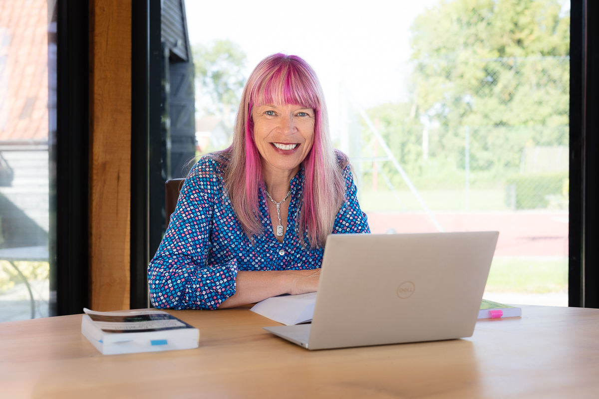 Woman with pink hair working on a laptop, photographed for FHM Forensic Accounting