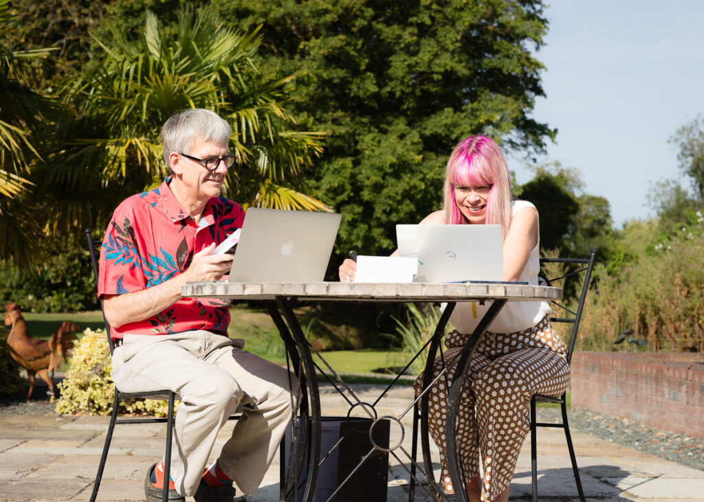 Two people working on laptops outdoors