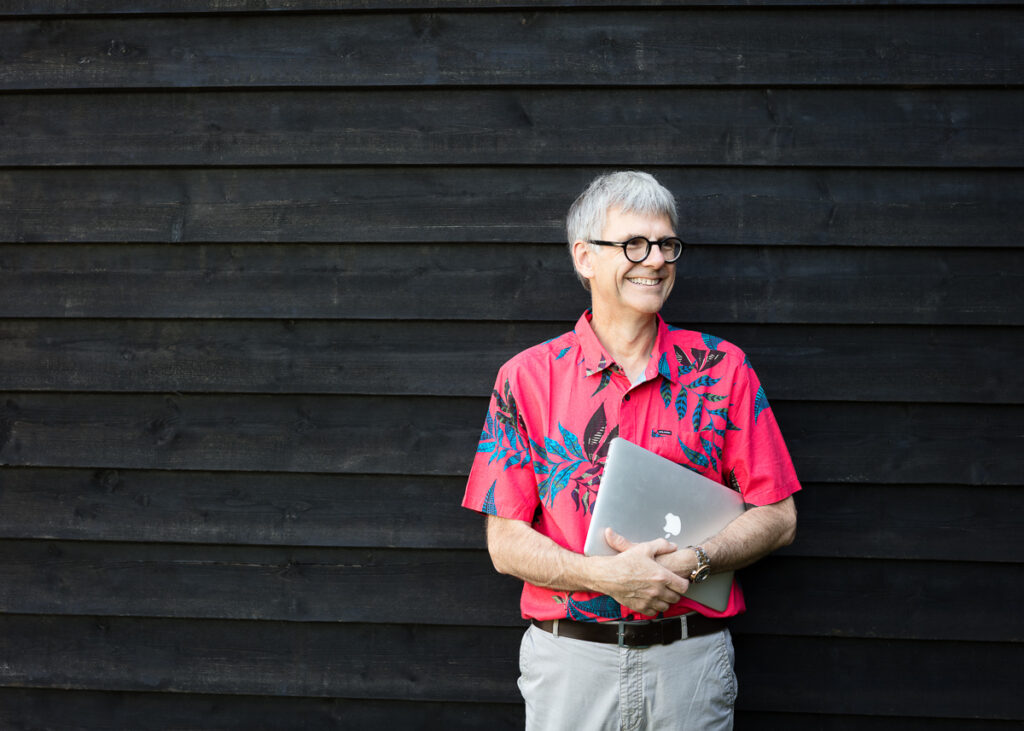 Man in floral shirt holding a laptop