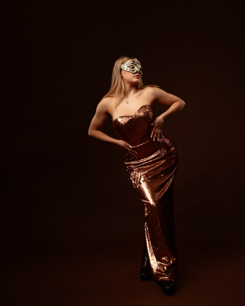 Woman in sequin dress wearing masquerade mask.