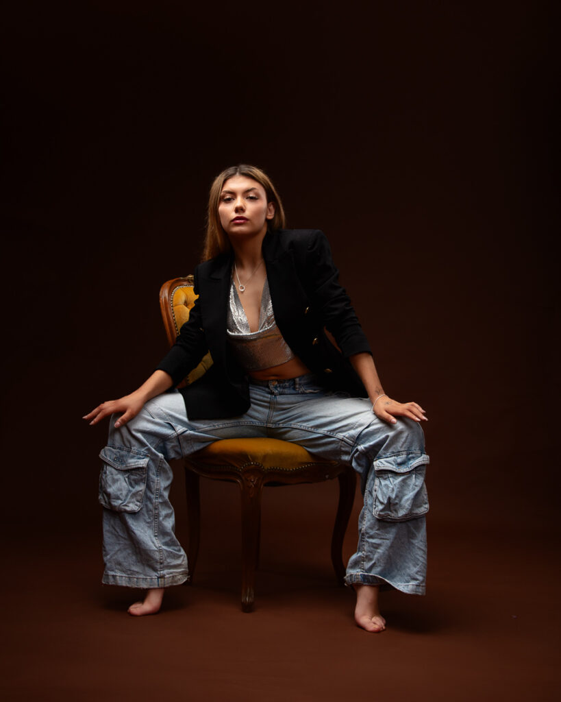 Woman in black blazer and jeans sitting on chair