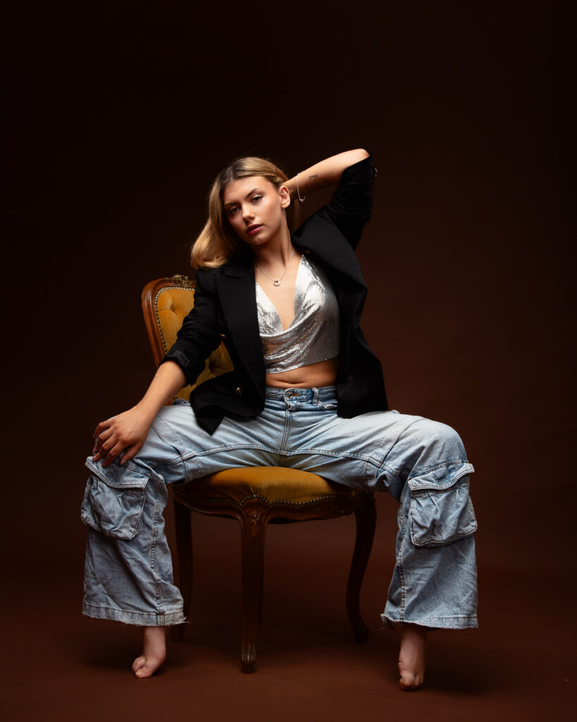 Woman posing on chair in stylish outfit.