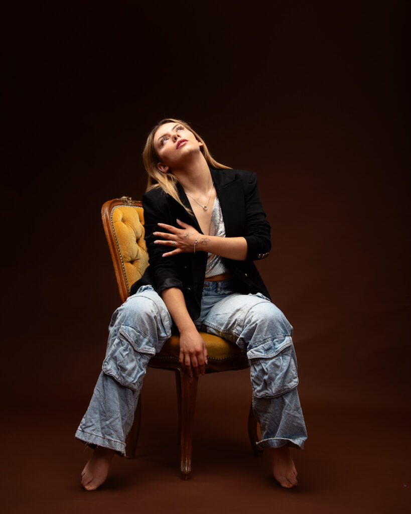 Woman sitting on chair, looking upwards thoughtfully.
