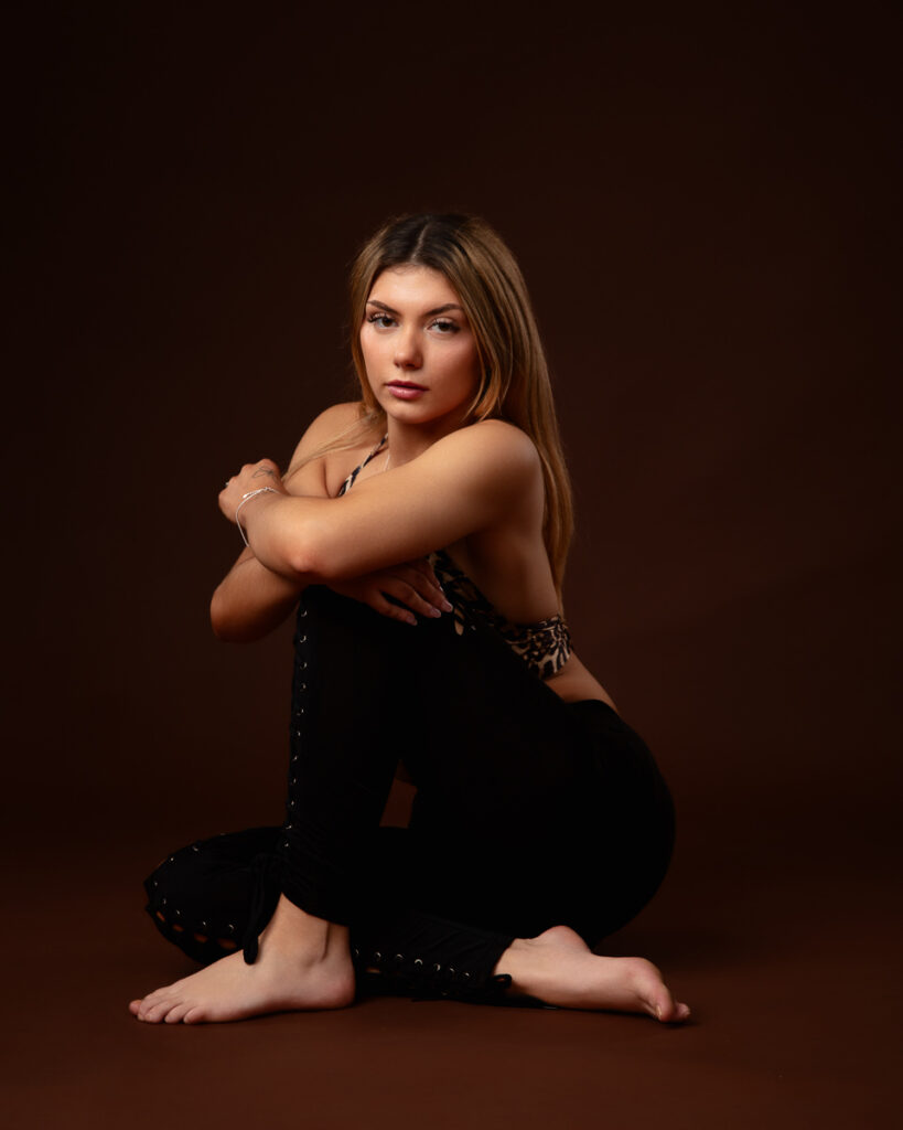 Woman seated posing against dark background