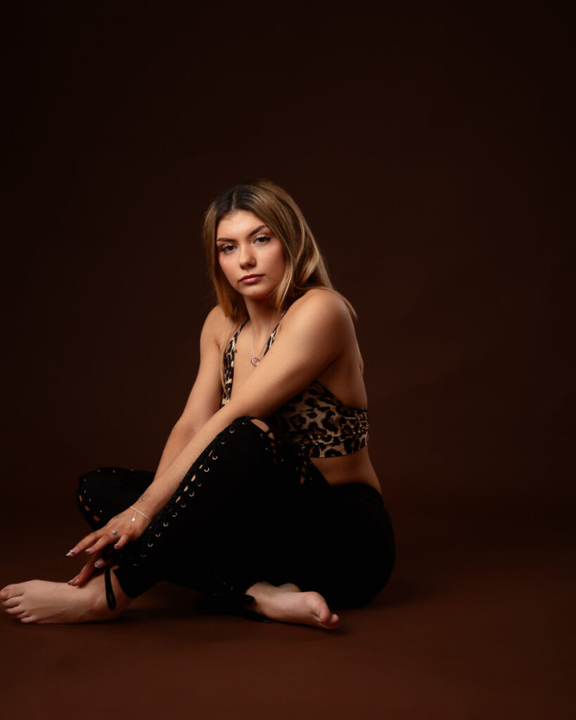 Woman sitting in leopard-print top, dark background