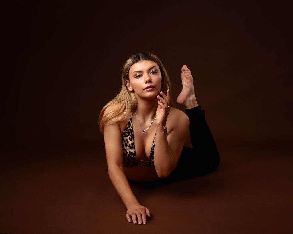 Woman posing in leopard-print outfit on brown background.