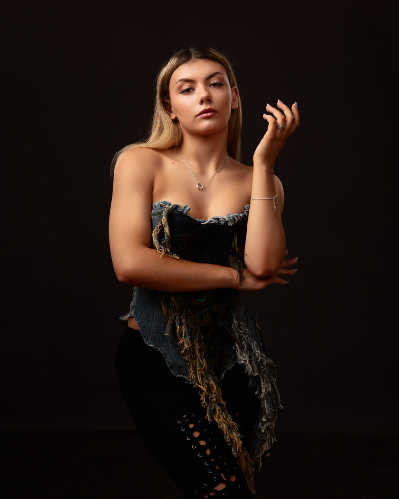 Woman in distressed denim top posing confidently