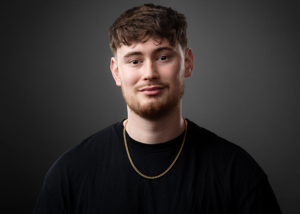 Man with beard and necklace against dark background