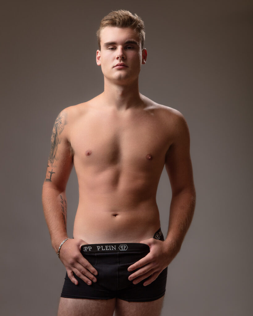 Shirtless man posing in black underwear.