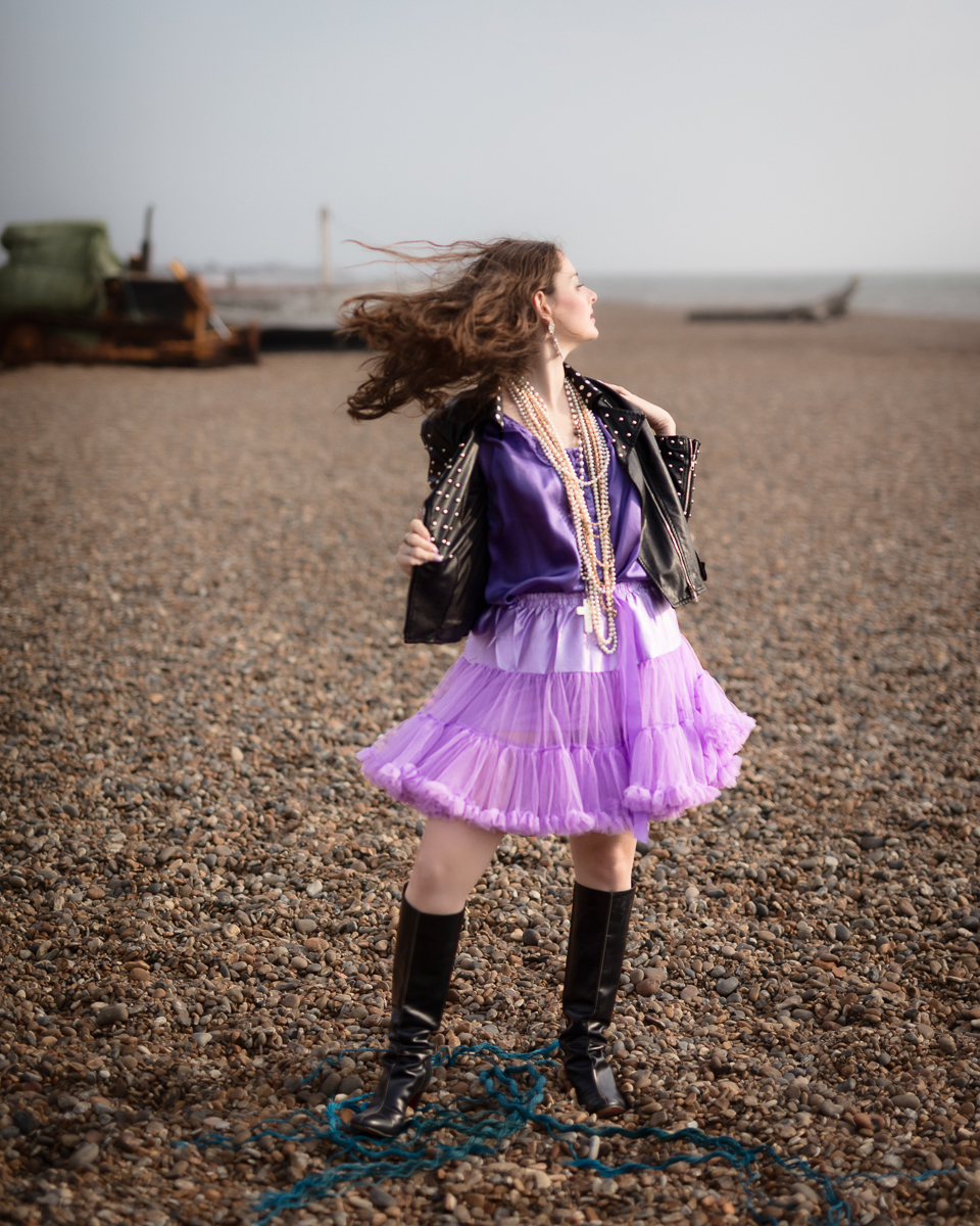 Woman in purple skirt on a pebble beach.