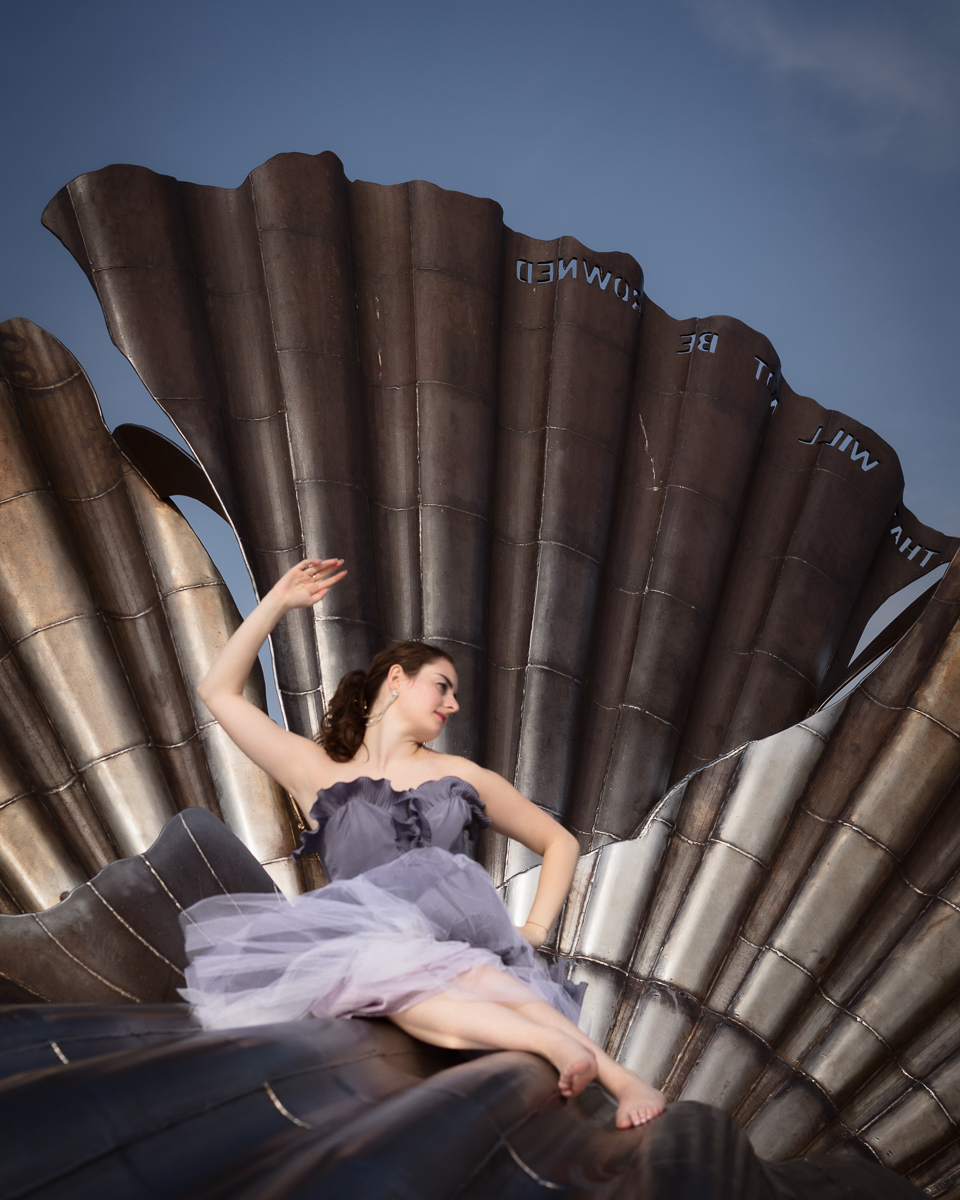 Woman posing on large metallic sculpture.