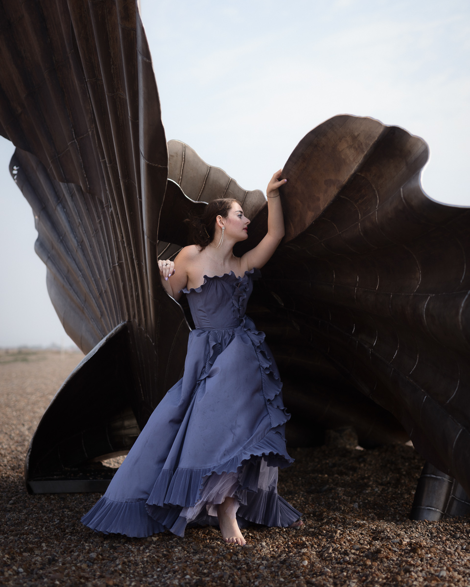 Woman in blue dress with large metal sculpture