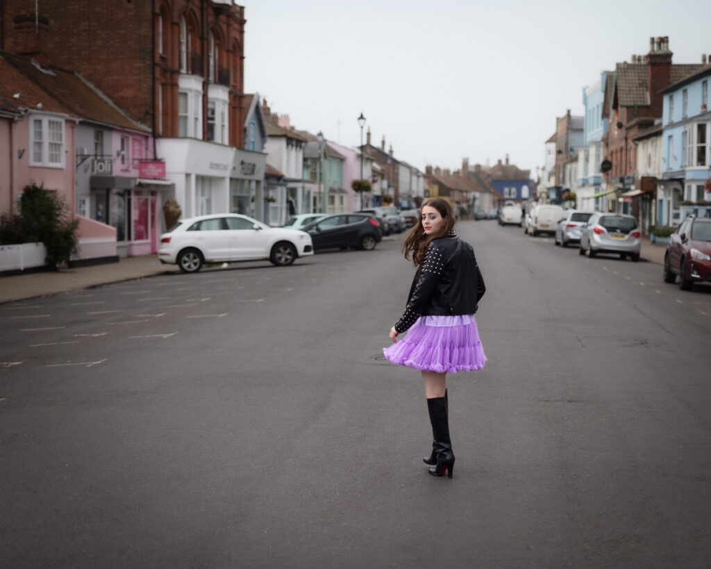 Woman in black jacket and purple skirt on street
