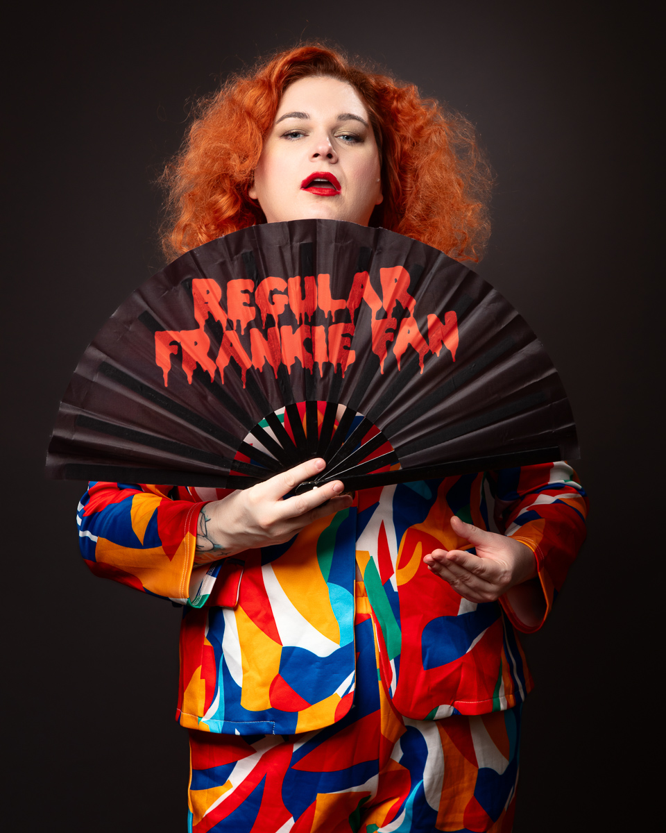 Person holding fan in colourful suit.