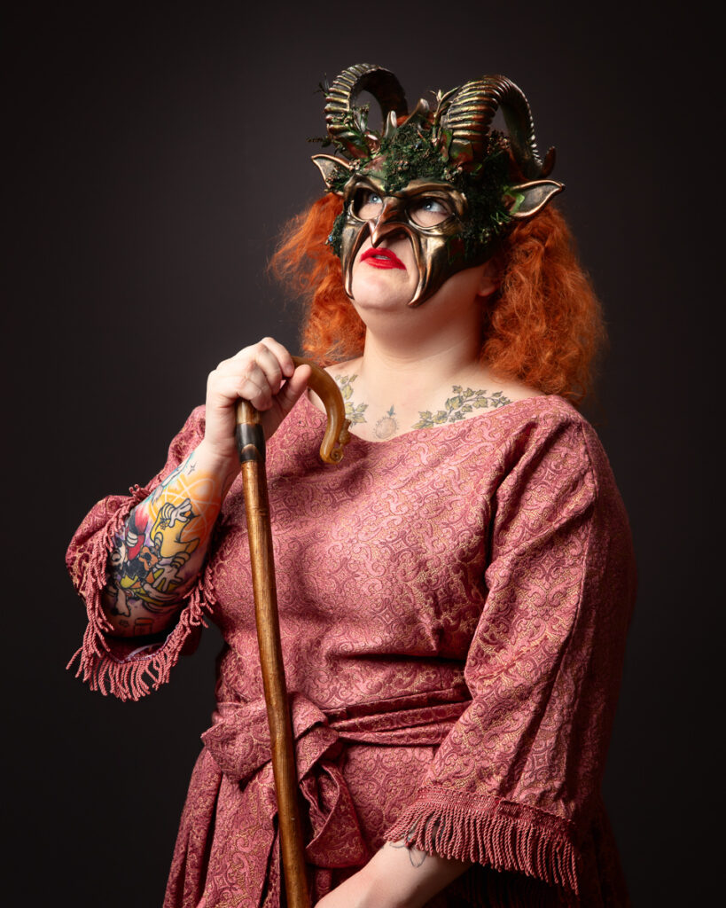 Person in costume with staff, wearing a horned mask.