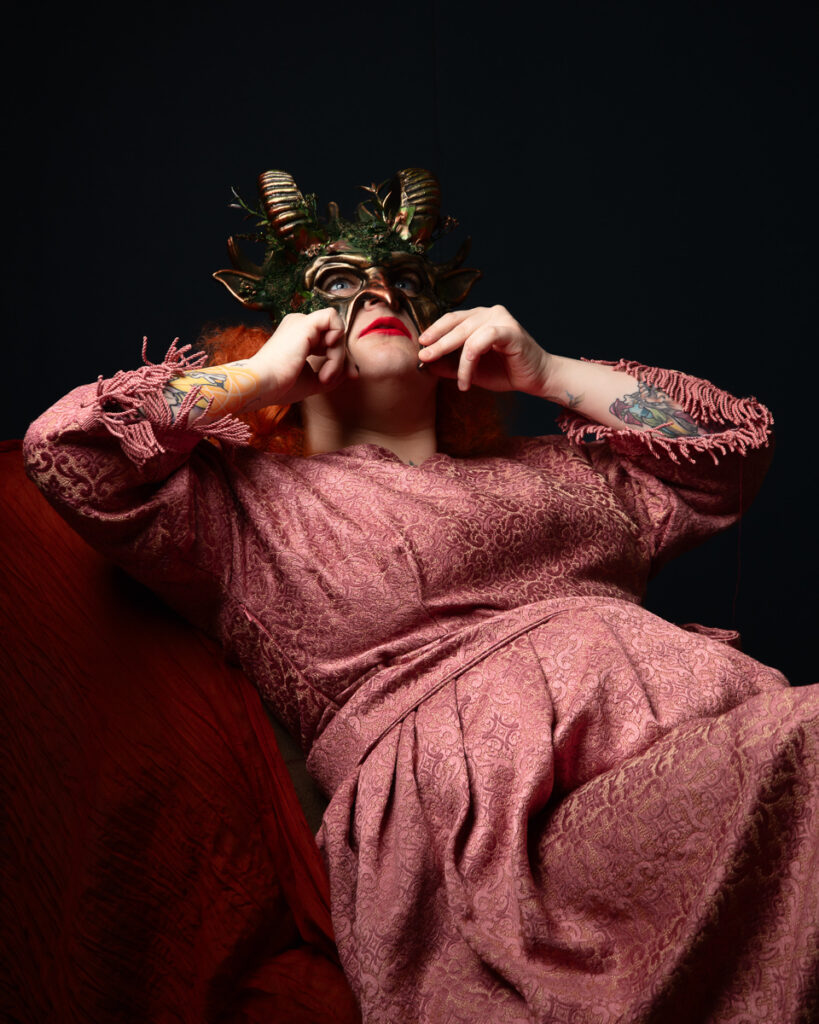 Person in ornate mask and pink dress posing