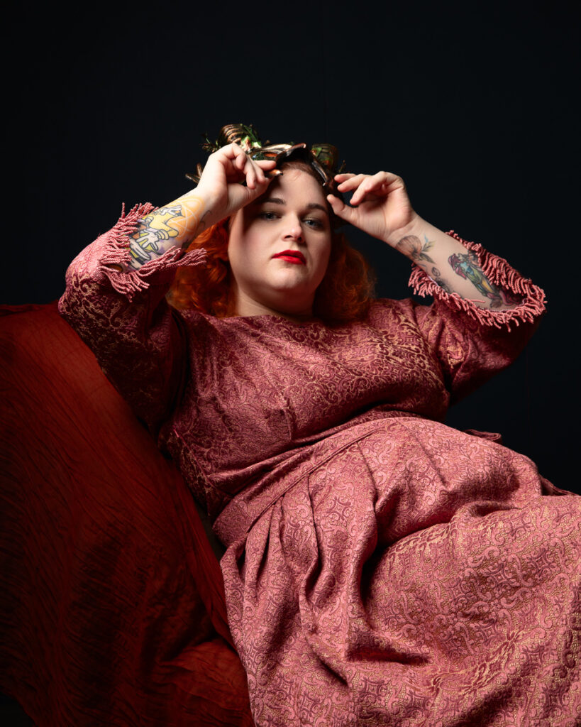 Person in red gown adjusting decorative headpiece