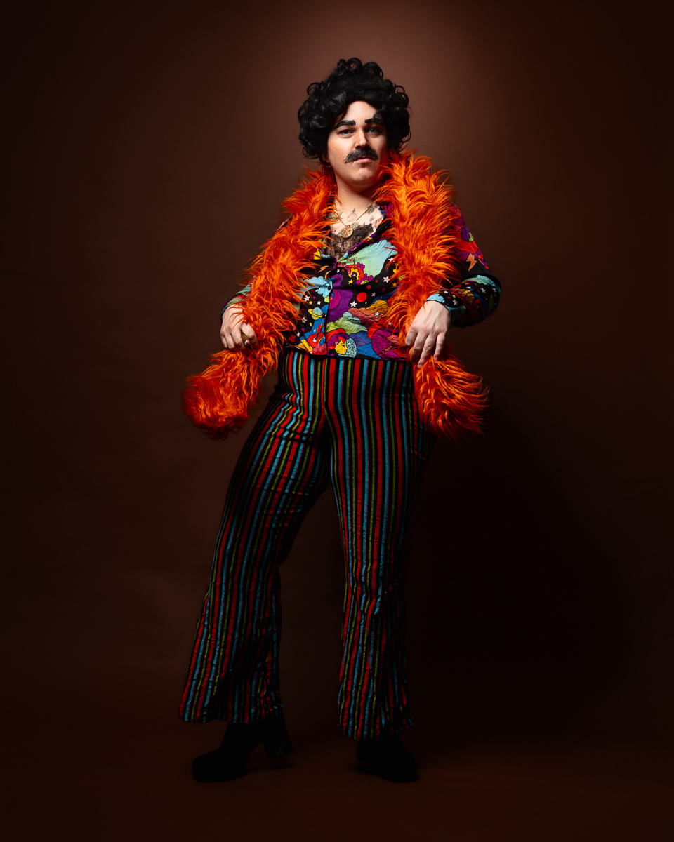 Person in colourful 70s costume with orange feather boa.