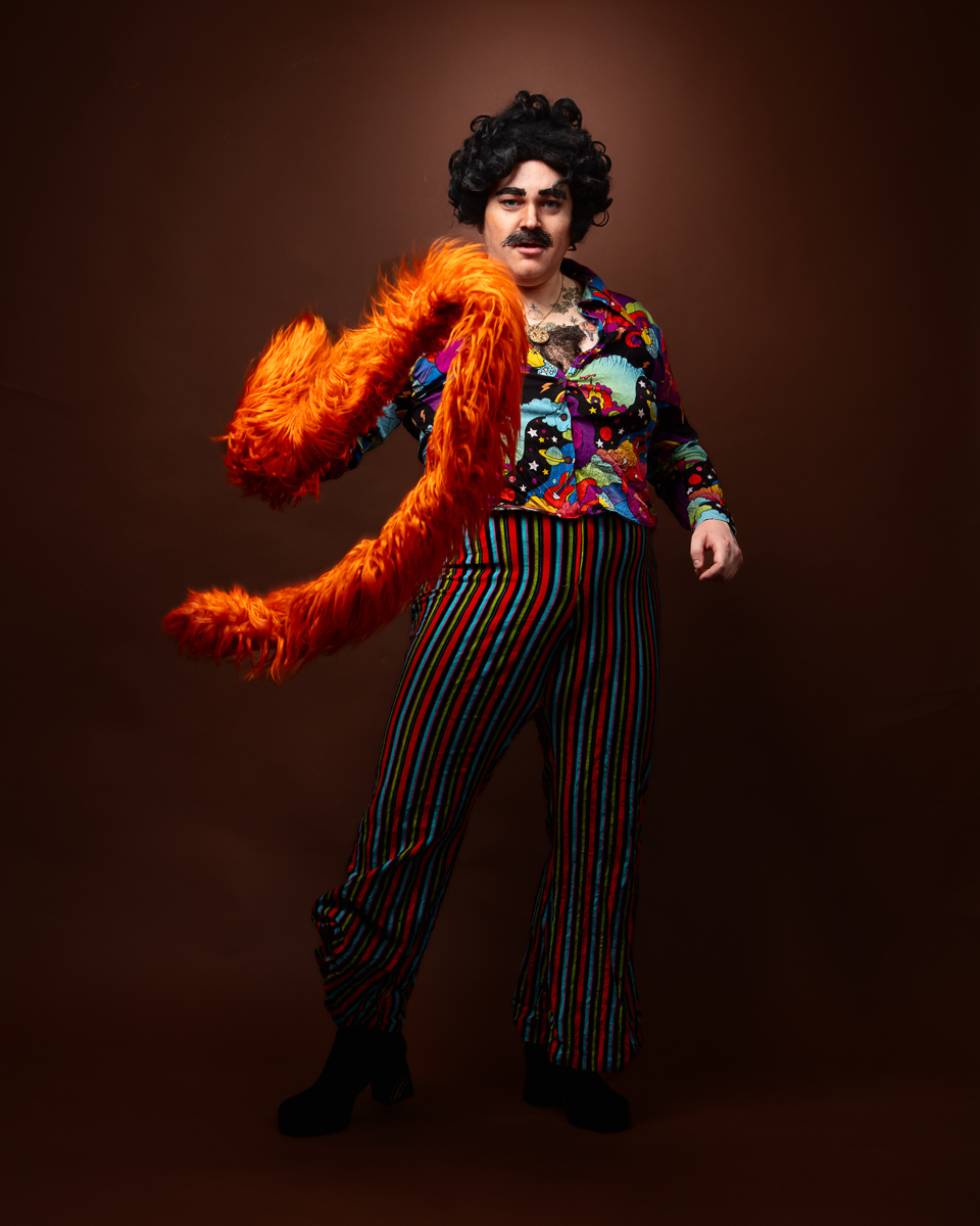 Person in colourful, retro 70s outfit posing.