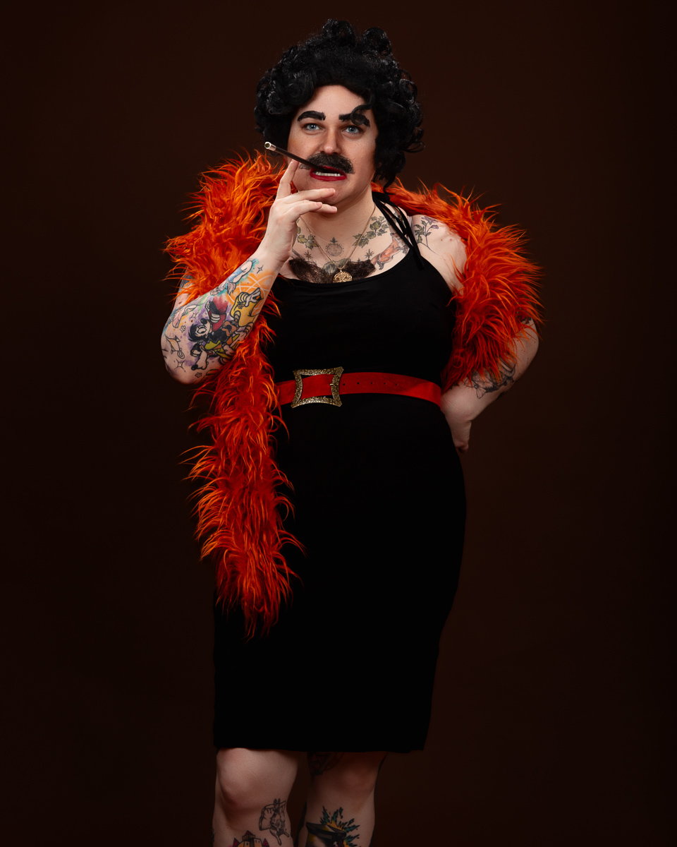 Person in costume with feathers and tattoos smoking.
