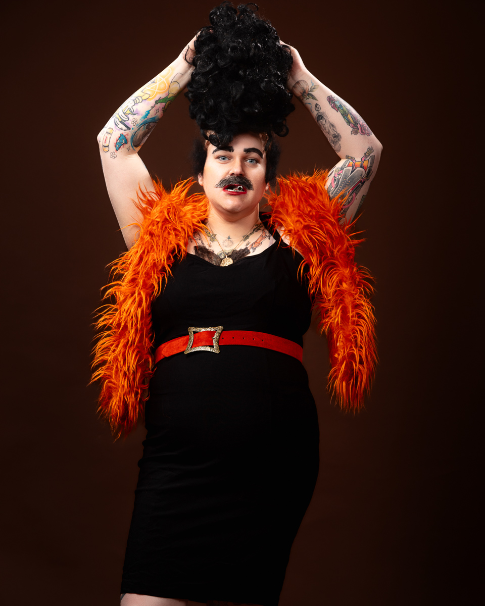 Person with tattoos posing in orange feather boa