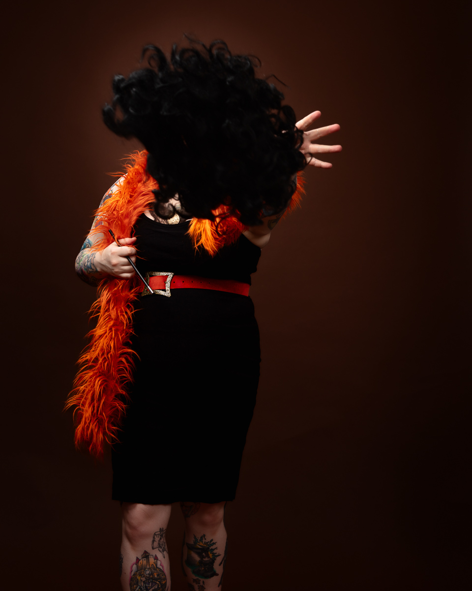 Person with tattoos wearing feather boa.