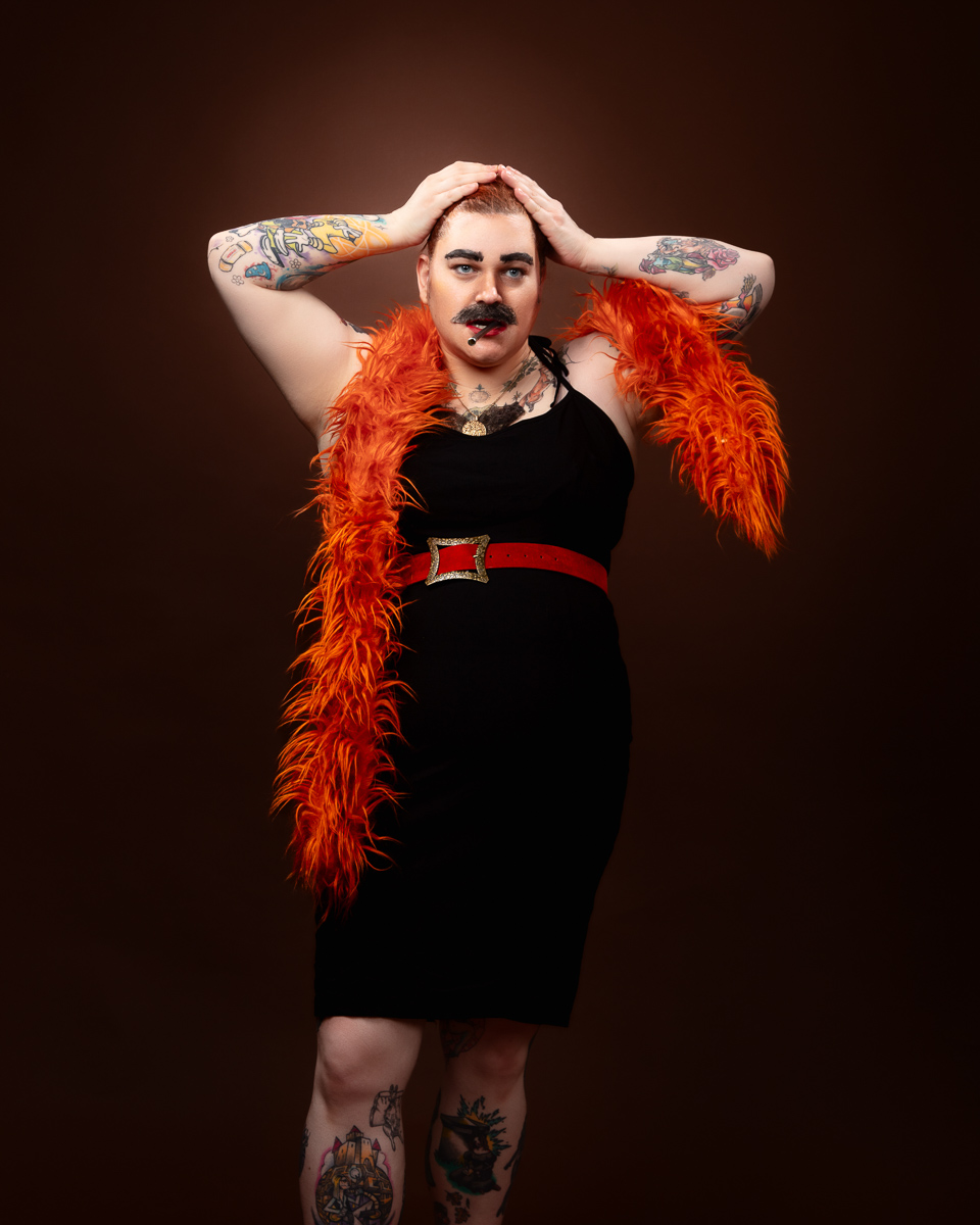 Person with tattoos wearing orange feather boa