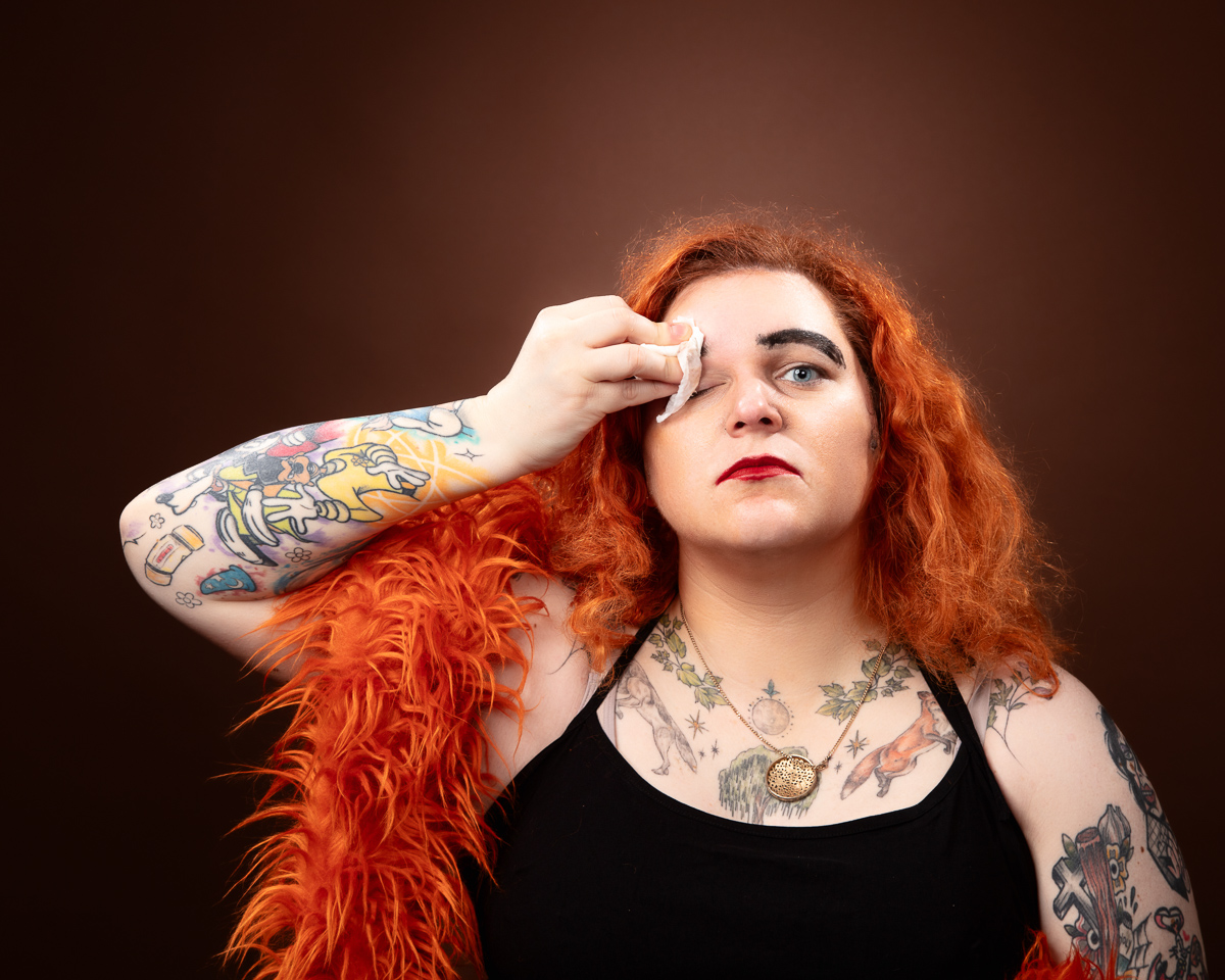Person with tattoos removing makeup with a wipe.