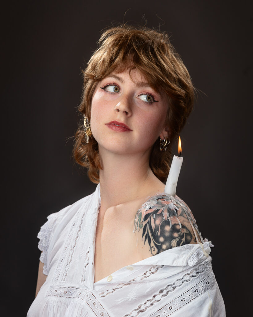 Person with shoulder tattoo and candle on shoulder.