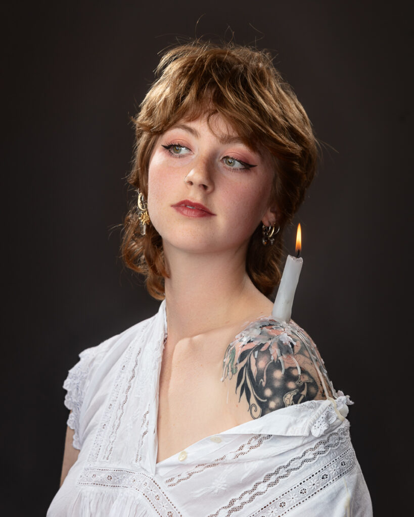 Woman with candle on shoulder tattoo, artistic portrait.
