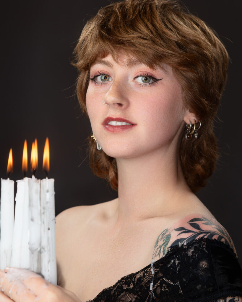 Woman holding lit candles and smiling.