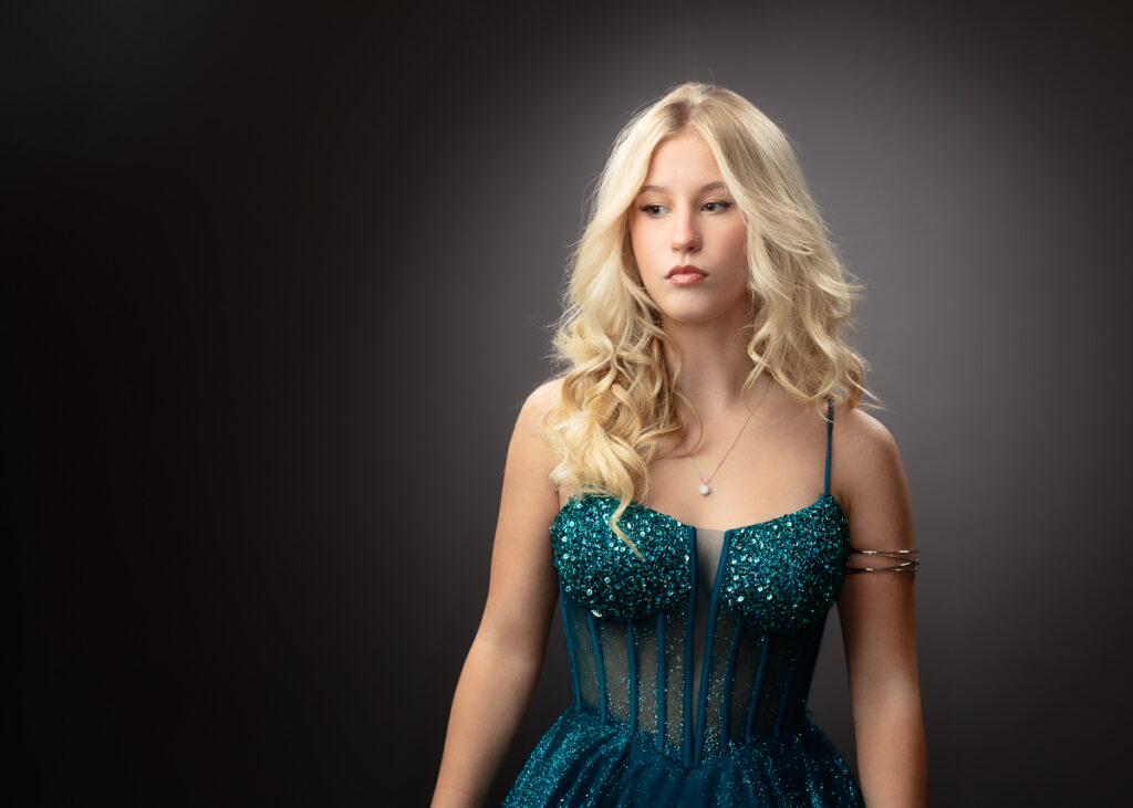 Blonde woman in teal sequined corset dress, studio portrait