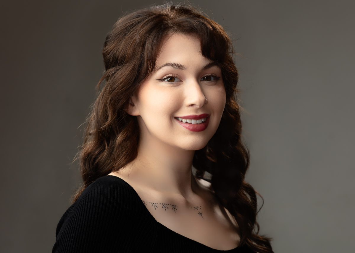 Smiling woman with brown curly hair.