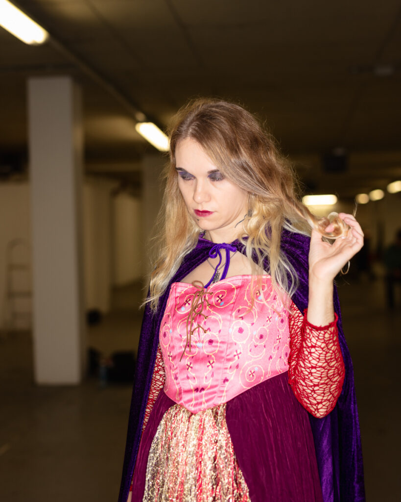 Woman in colourful medieval-style costume indoors.