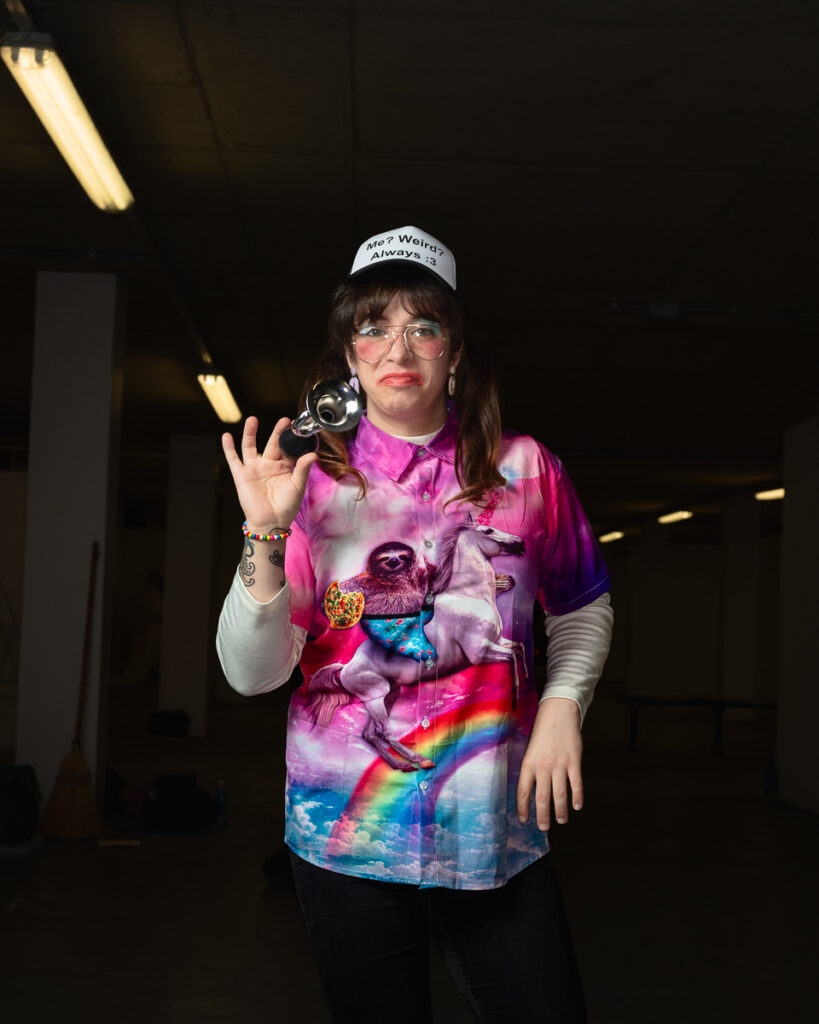 Person wearing vibrant sloth shirt and cap holding camera
