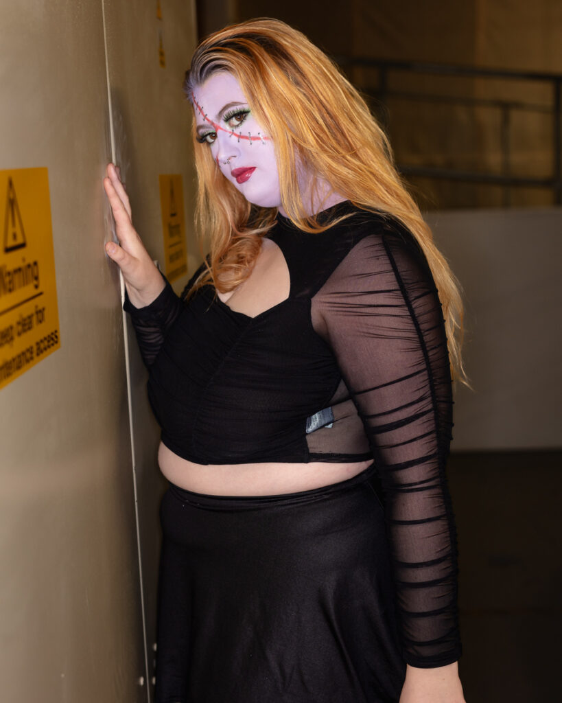Person with stitch makeup and black outfit posing