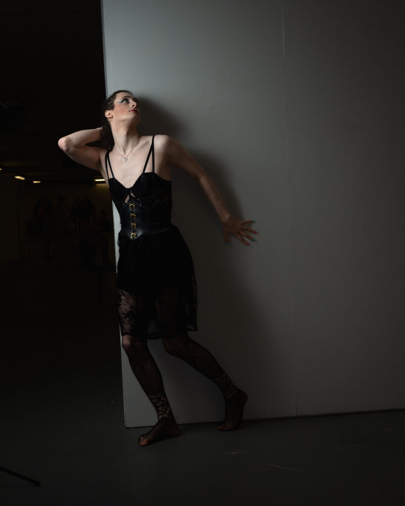 Woman in black corset dress against white wall