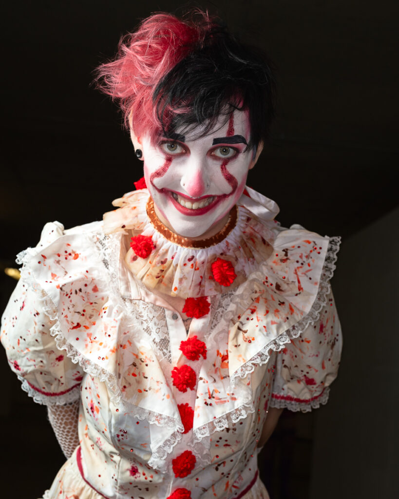 Theatrical clown performer with pink hair and red makeup