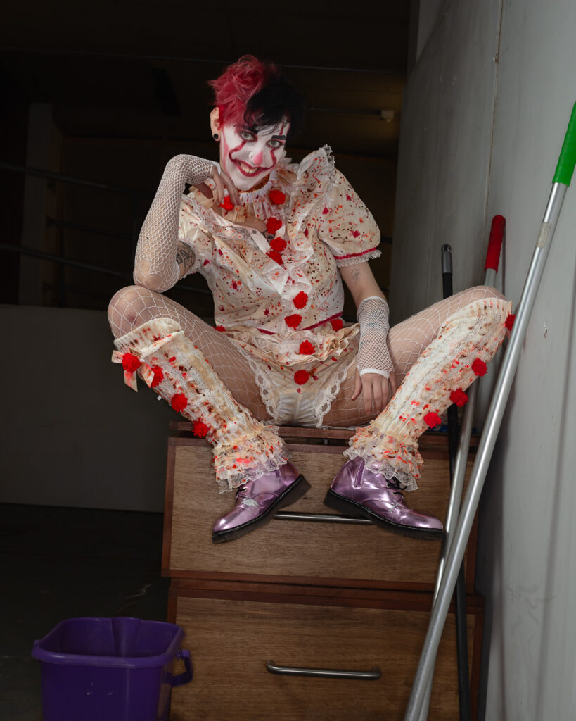Person in elaborate clown costume with pink hair and makeup
