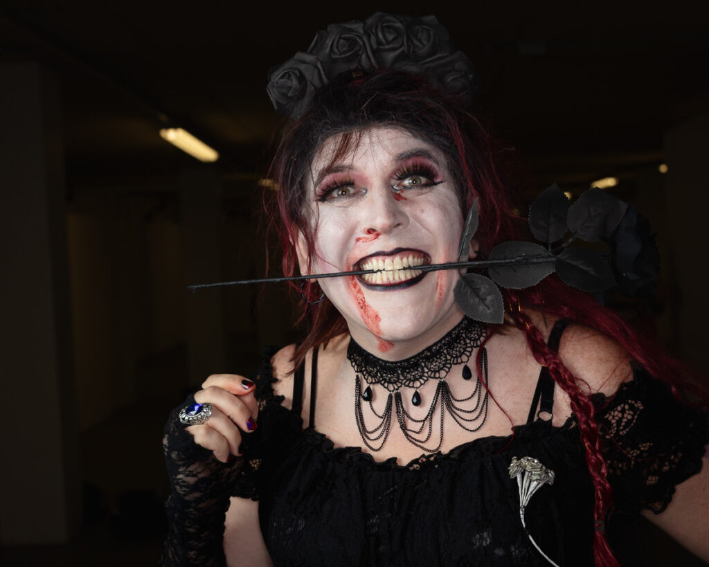 Gothic woman with dark rose in mouth, dramatic makeup