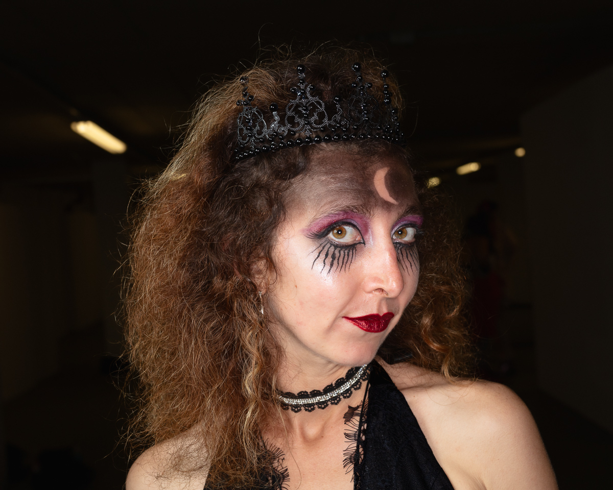 Woman with theatrical makeup wearing ornate tiara and choker